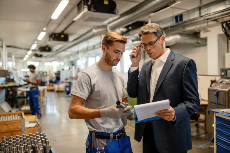 Ingeniero y operario analizando reportes de producción en planta metalmecánica