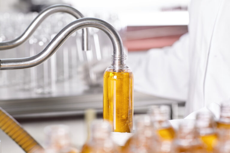 Llenado de una botella plástica en una línea de envasado industrial